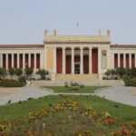 The entrance of the National Archaeological Museum with stairs, flowers and trees.