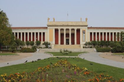 The entrance of the National Archaeological Museum with stairs, flowers and trees.