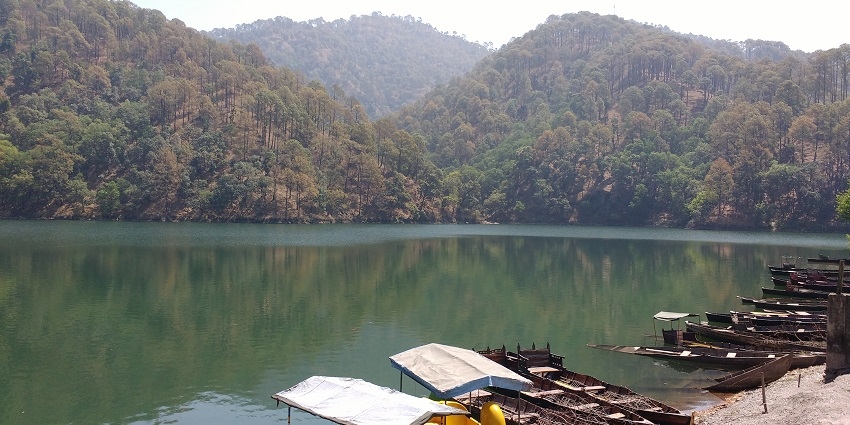 A beautiful lake at Naukuchiatal, with surrounding green hills, a peaceful getaway near Corbett.