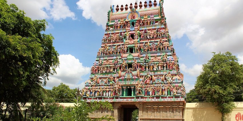 Outside the Thiruvenkadu temple with detailed architecture and devotees entering the temple.
