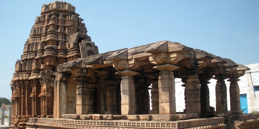 Entrance gate of Navasakthi Vinayagar Temple with people walking and a sign in Tamil