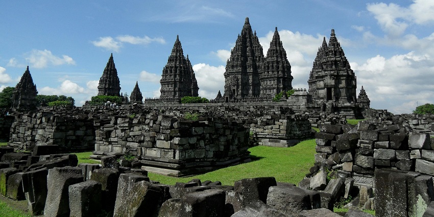 An image of grey concrete temples set against a blue and white cloudy sky background.