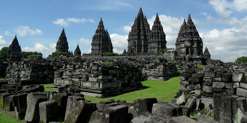 An image showing gray concrete temples set beneath a blue sky with scattered white clouds.