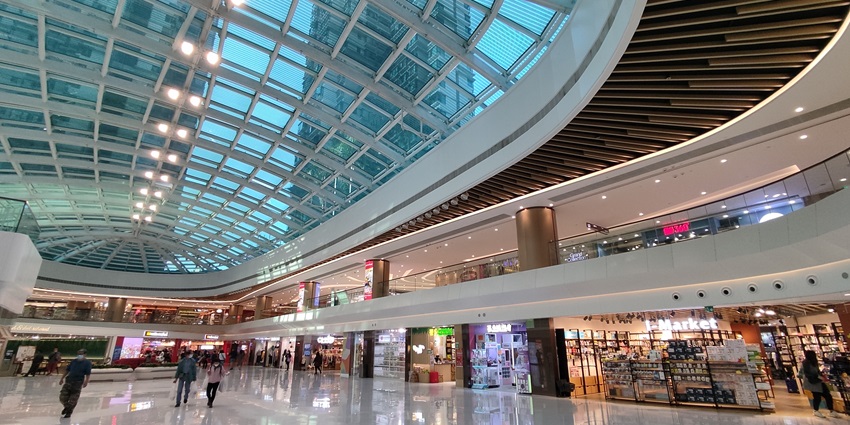 Interior of Metro City Plaza mall atrium with curved escalators and light-filled void.
