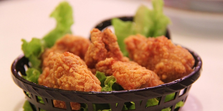 Close-up view of several pieces of fried chicken contained in a brown plastic container