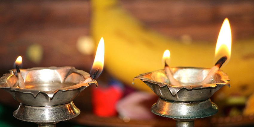 Two brass oil lamps glowing and softly burning, placed at the altar in a temple.