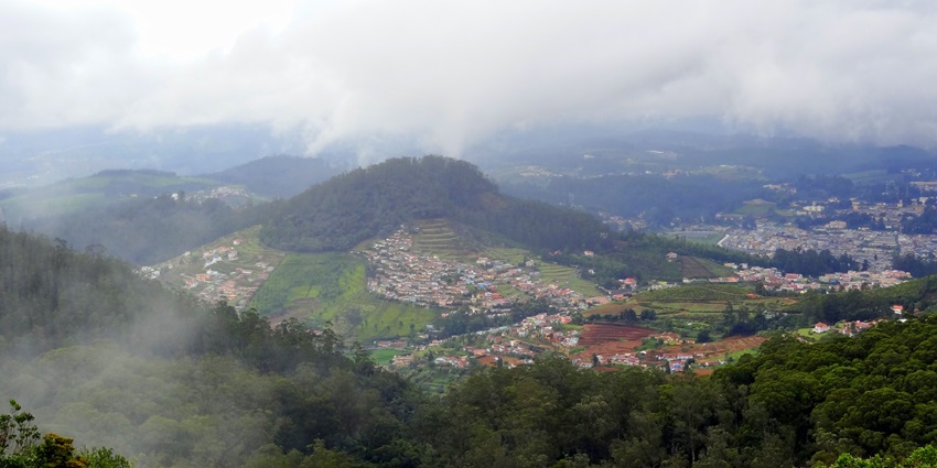 A picture of Ooty, a beautiful hill station, surrounded by tea plantations and misty hills.