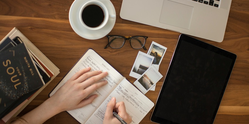 An image of travel things - a camera, a diary, a travel itinerary and many more.