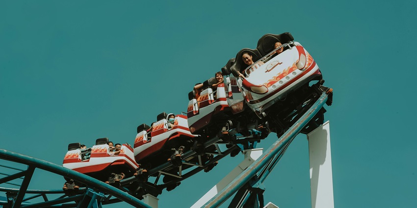 An image showing a high-speed rollercoaster at an amusement park with excited riders.