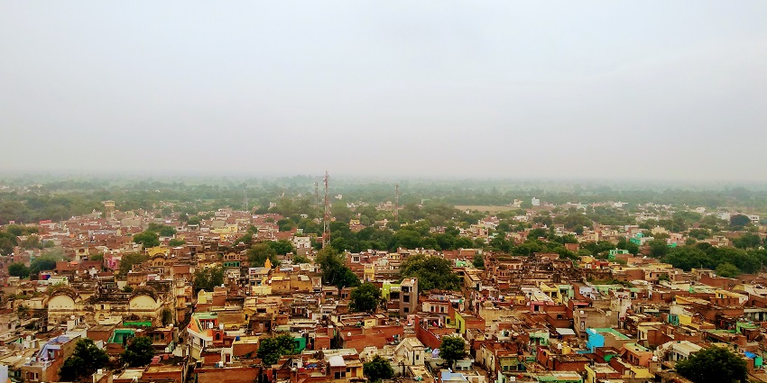 A scenic view from Shriji Temple, Barsana: a hilltop with temples, trees, and houses in the distance.