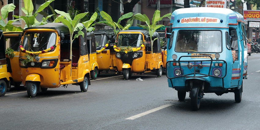 Colourful auto rickshaws lined up on a bustling street in Puducherry with local shops