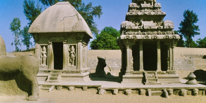 The inside of the Ratha Temple with trees in the background and sand on the floor.