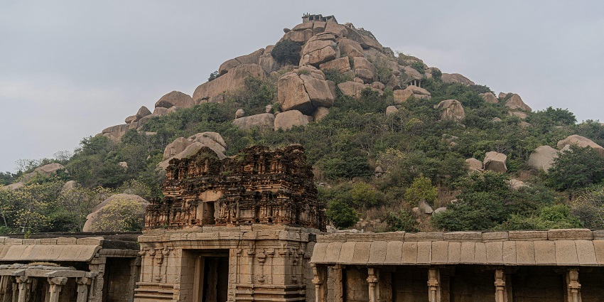 A picture of the ruins of a temple at a mountain, surrounded by lush greenery