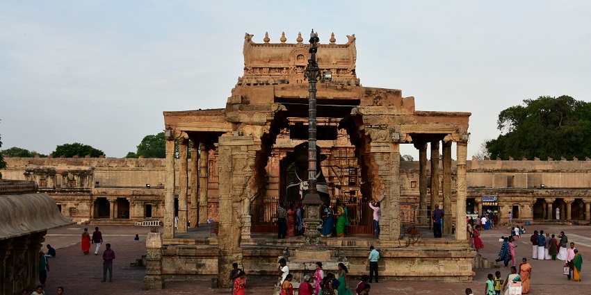 People walking in the Brihadishwara Temple complex near the majestic Nandi statue.