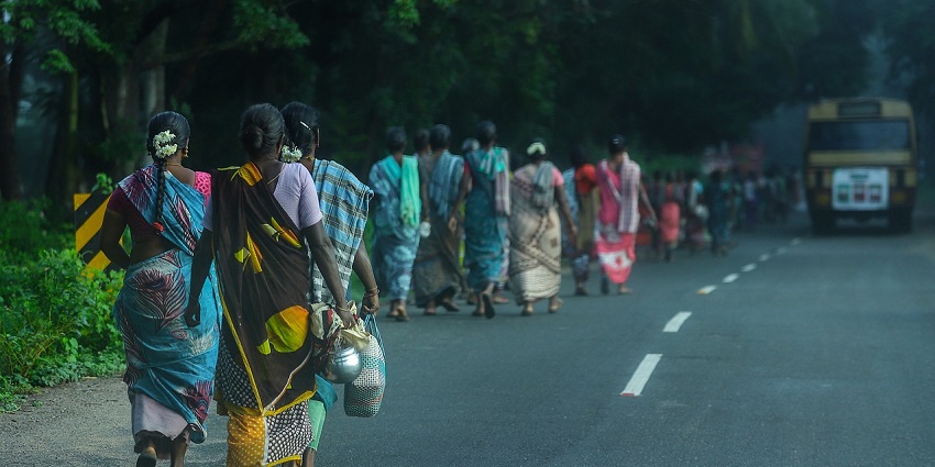 Women wearing sarees walking in the streets of Tamil Nadu with things in one hand