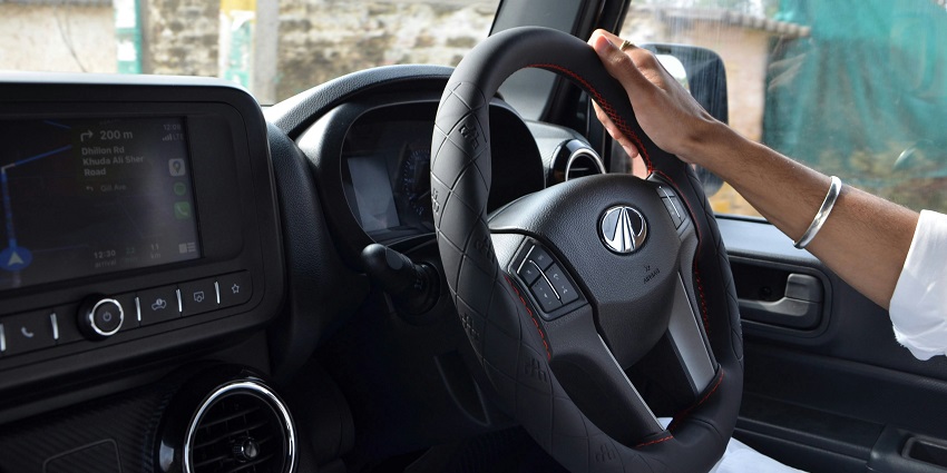 A man driving a car, with hands on the steering wheel, focused on the road ahead
