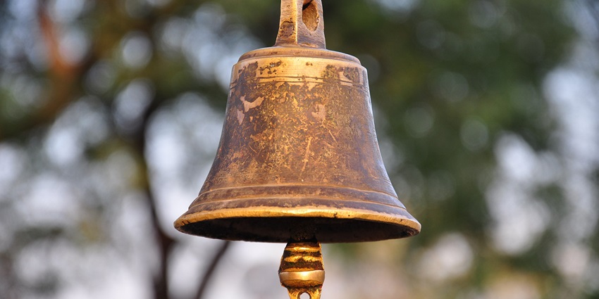 Ornate bell at the Thousand Pillar Temple, hanging amidst intricately carved stone pillars