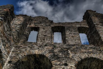 An image of a ruined stone wall with arched windows at a Fort which resembles the Padmadurg fort in Maharashtra.