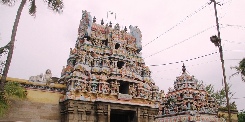 A picture of a temple with beautiful bright paints and a tall gopuram with intricate carvings