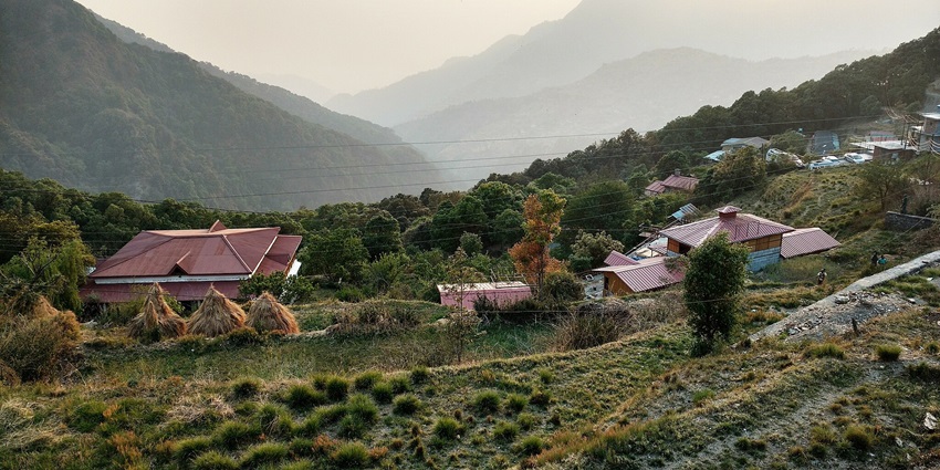 A small village in Uttarakhand's mountains with trees and greenery all around