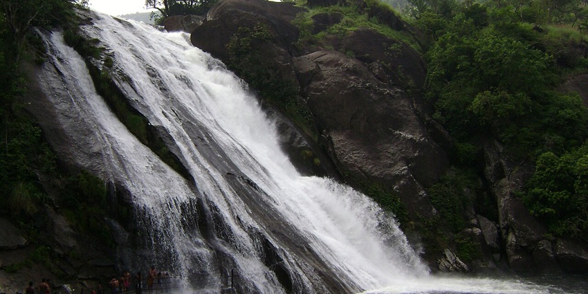 An image of Papanasam Waterfall surrounded by green trees located in the Western Ghats.