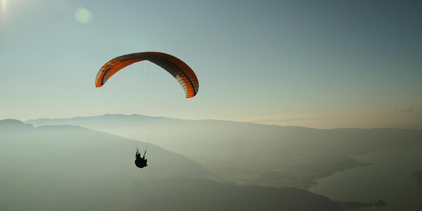 A stunning aerial view of a person using a parachute while paragliding in the sky.