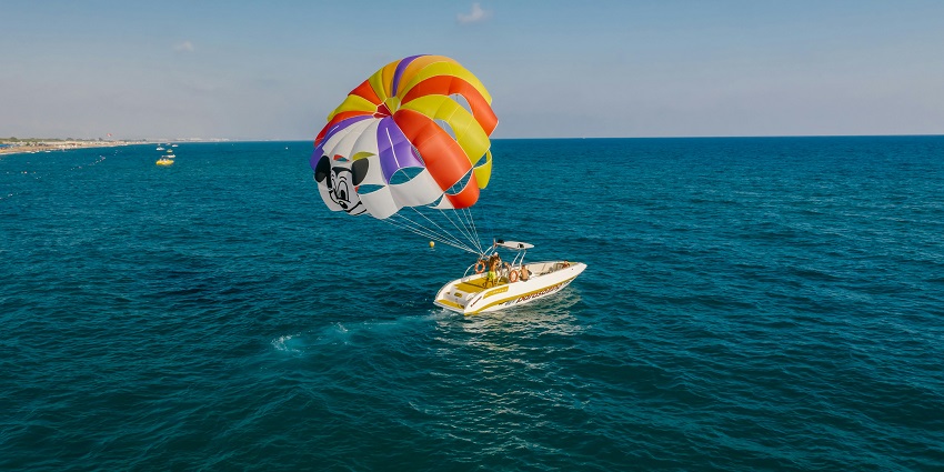 An image of a person parasailing high, one of the top Juhu Beach water sports.