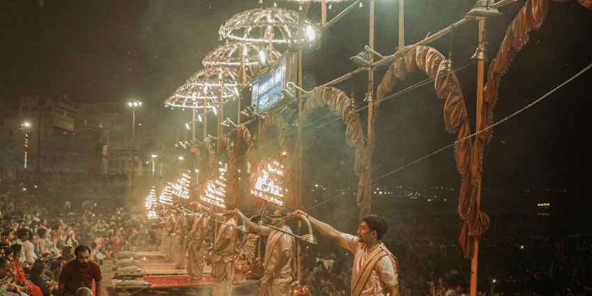 An image of the hindu priests performing the Aarti ceremony at the ghats at night.
