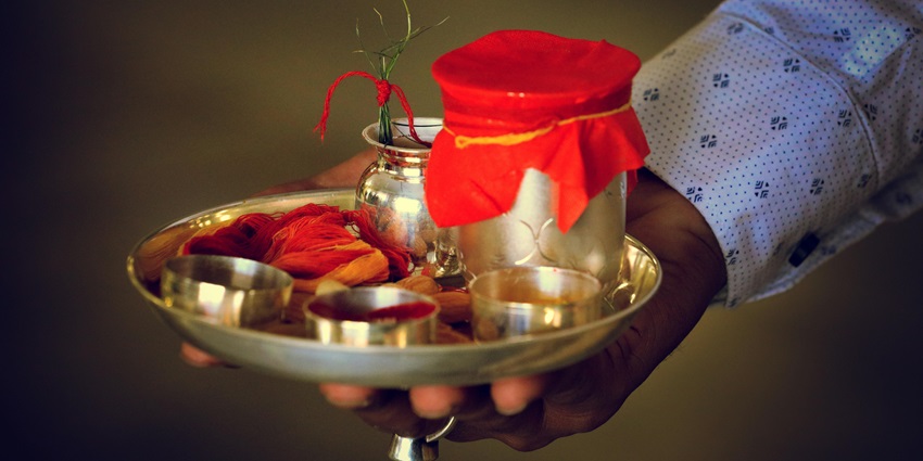 An image of a person holding the puja thaal to participate in the daily rituals.