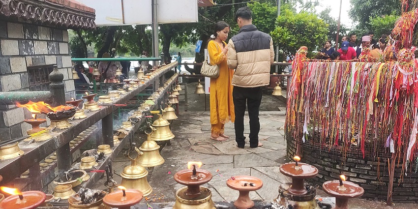 A man and a woman performing a ritual outside the temple with a group of people in the background