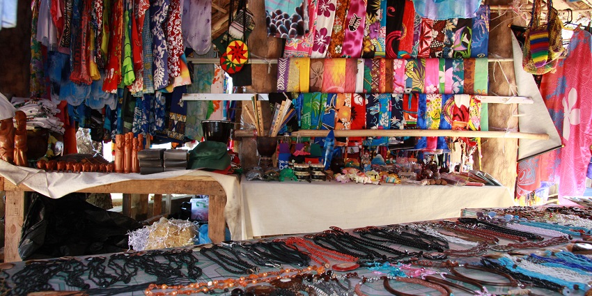 Colourful handicraft stall with vibrant woven bags, hats, and handmade items on display.