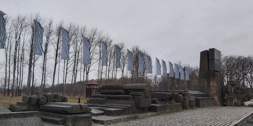 International monument with old structures, multiple flags, and dried-out winter trees.