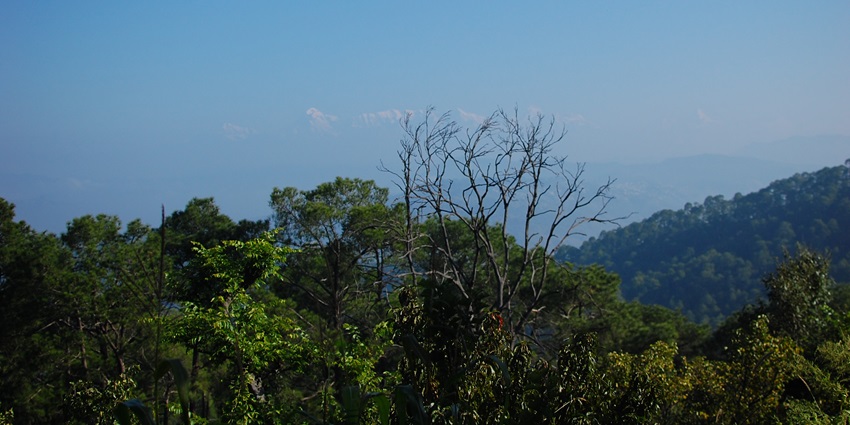 Snow‑capped Himalayan peaks visible beyond lush green hills-less crowded hill stations in uttarakhand