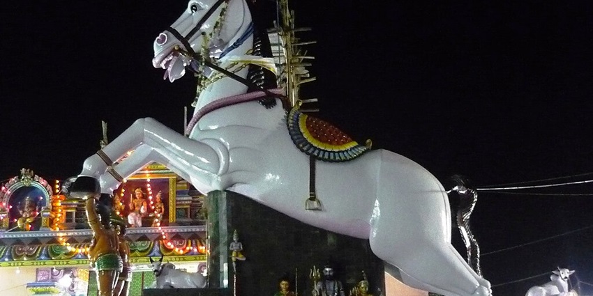 A tall horse figure at Kulamangalam Ayyanar Temple, surrounded by other deity sculptures.