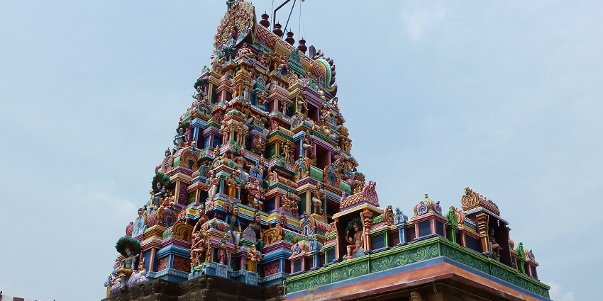 Perur Pateeswarar Temple with detailed carvings and stone architecture against a clear sky.