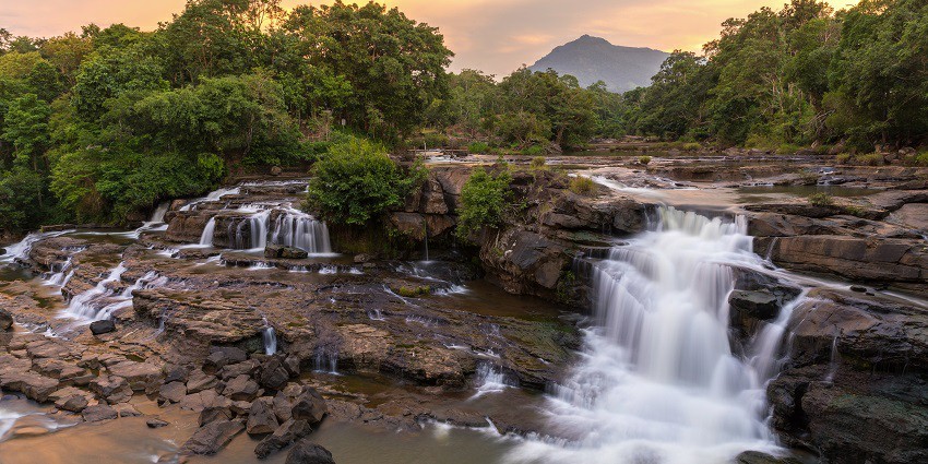 Beautiful Phurlijharan Waterfall cascading down rocky cliffs, surrounded by dense greenery