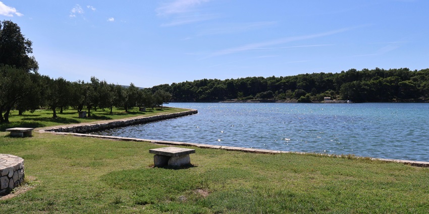Scenic coastal park view with benches overlooking shoreline under blue skies