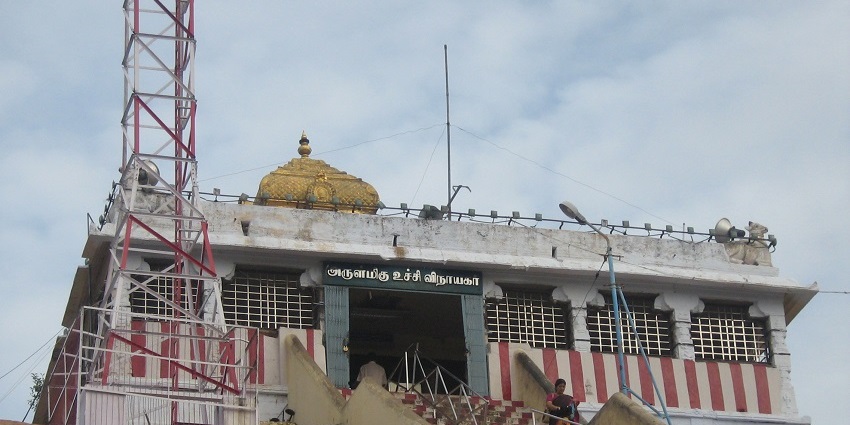 Pillayar Koil temple with golden dome, striped walls, and antenna tower on a rocky hill.