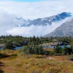 A scenic view of Alaskan sky, highlands and mountains covered with clouds