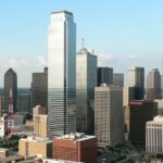 Tall skyscrapers of Dallas with glass buildings and an advertisement banner on the road