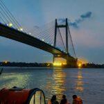 A serene capture of people riding a boat on a body of water during the evening in Kolkata.