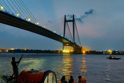 A serene capture of people riding a boat on a body of water during the evening in Kolkata.