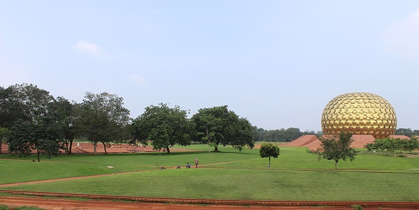 The golden spherical meditation centre dome of Auroville ashram in huge open ground.