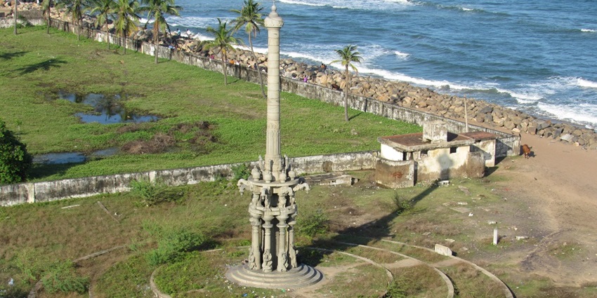 An idyllic view of Poombuhar featuring a towering lighthouse and a serene beach.
