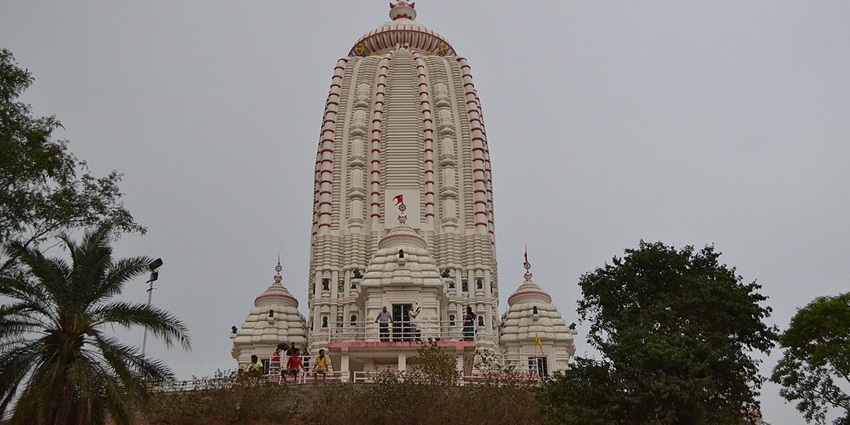 View of the  intricate architecture of Prachin Ram Mandir, surrounded by lush trees.