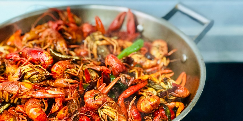 A lip-smacking view of a dish served with cooked prawns sitting on a gas stove.