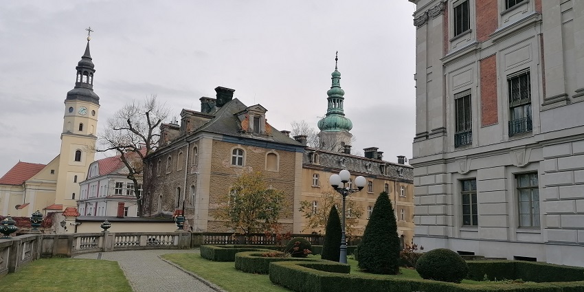 Pszczyna castle with detailed architecture, a cross on top of the castle and a bench.