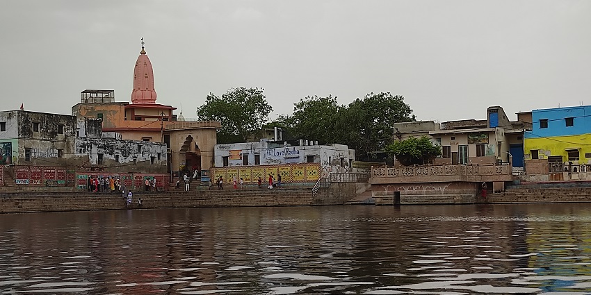 An image of Radha Kund, a famous place near Gokul Temple, featuring clear waters and greenery.