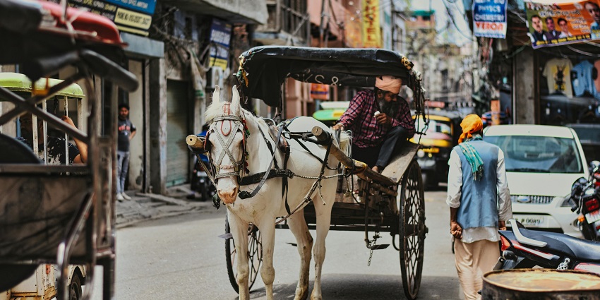 A picture of a street market showing a man pulling a horse cart