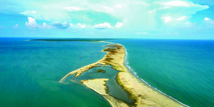 Aerial view of Adam’s Bridge across a stretch of blue water and a clear sky in the backdrop